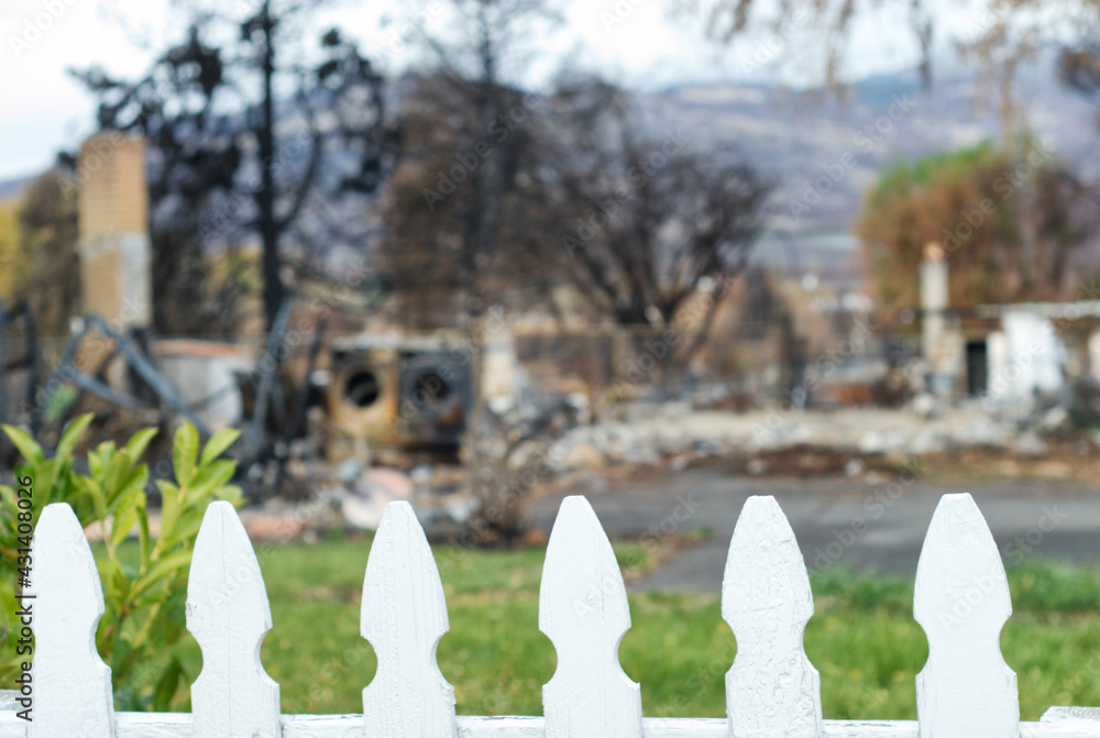 Naklejka premium White picket fence in front of a burned down house.