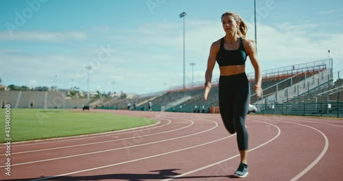 Young athletic woman running at stadium track, working hard and pushing the limits of her body, sprinting to the finish line, active lifestyle