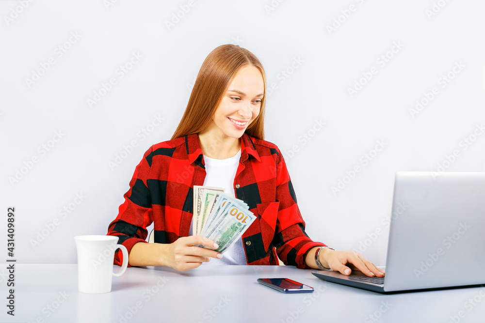  Happy smiling business woman working online on computer earning money dollar bills banknotes.  Online shopping, e-commerce, internet banking, spending money, working from home concept.