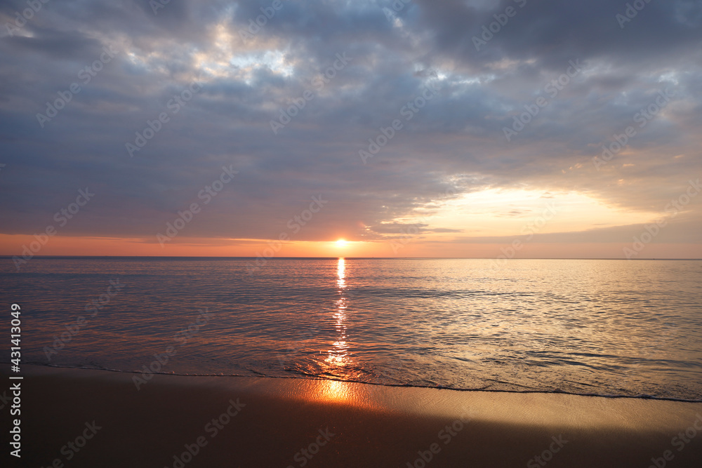 Beautiful sunset over the clam sea with cloud sky background. Sunset over tropical beach. Nature summer  concept. Peak sunset over sea with yellow light reflect on sea water. Tranquil seascape. 