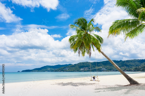Fototapeta Naklejka Na Ścianę i Meble -  Phukdt, Thailand. Tropical beach paradise with beach swing with girl in white shirt Women relax on swing under coconut palm tree at beautiful tropical beach White sand. Vacation summer holiday concept