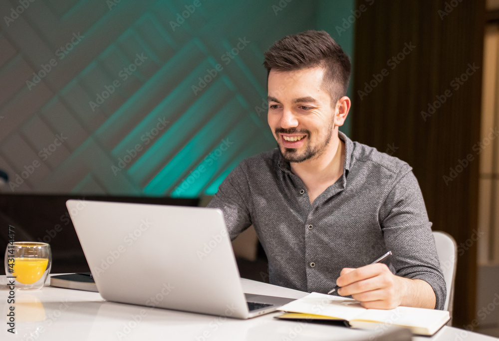 The young bearded man writes in a diary while working from home. The young bearded man writes in a diary while working from home.