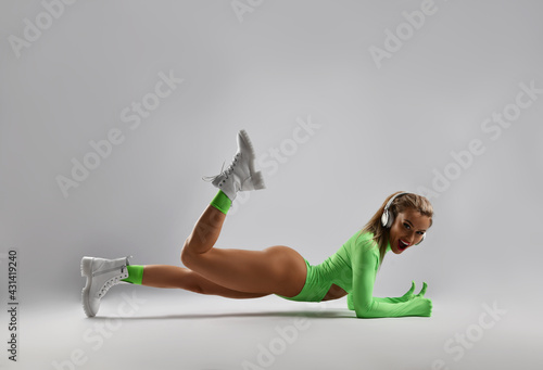 Εκτύπωση καμβά Happy, laughing blonde woman wearing stylish green sportswear bodysuit with long
