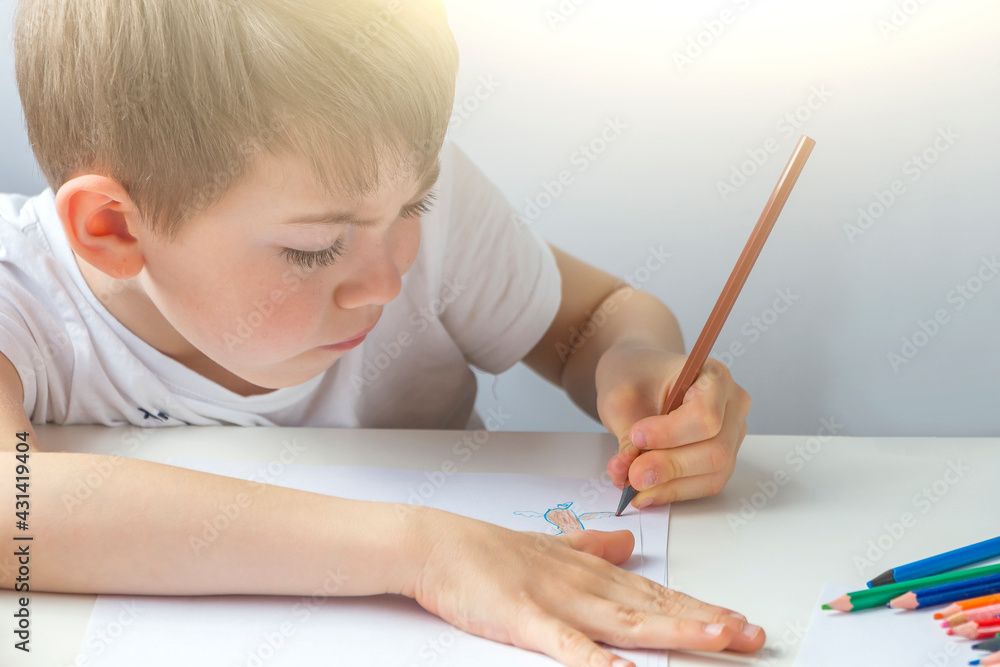 Focused preschooler little boy 5-6 years painstakingly draws drawing by pencil. Doing homework, drawing, education and child development. Childs creativity and art Focused preschooler little boy 5-6 years painstakingly draws drawing by pencil. Doing homework, drawing, education and child development. Childs creativity and art