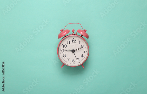 Pink alarm clock on mint green background. Minimalism. Top view. Flat lay