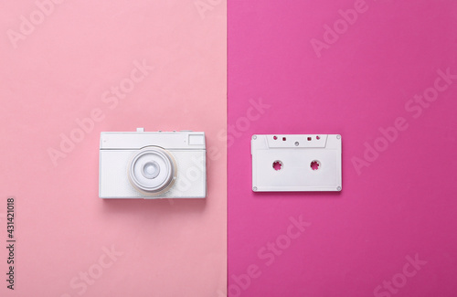 Creative retro layout. White retro camera and audio cassette on pink background. Inspiration. Fresh idea. Minimalism. Concept art. Modern still life. Flat lay. Top view.