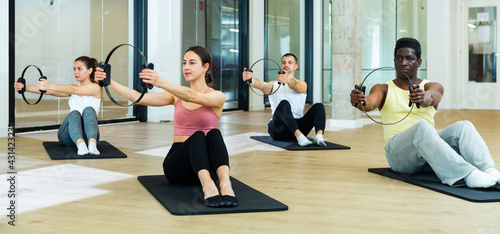 Multiethnic group of sporty people performing set of pilates exercises with Magic Circles in fitness studio