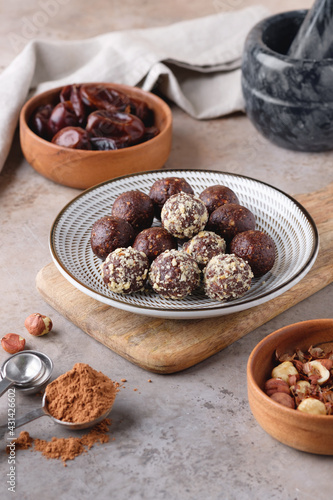 A plate with homemade raw chocolate energy balls, dates and hazelnut. Healthy vegan and vegetarian food.