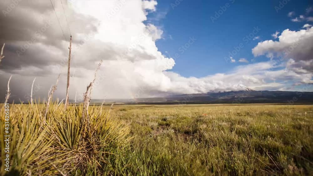 Rainbow time lapse of a field with snow cap mountains in the background Rainbow time lapse of a field with snow cap mountains in the background