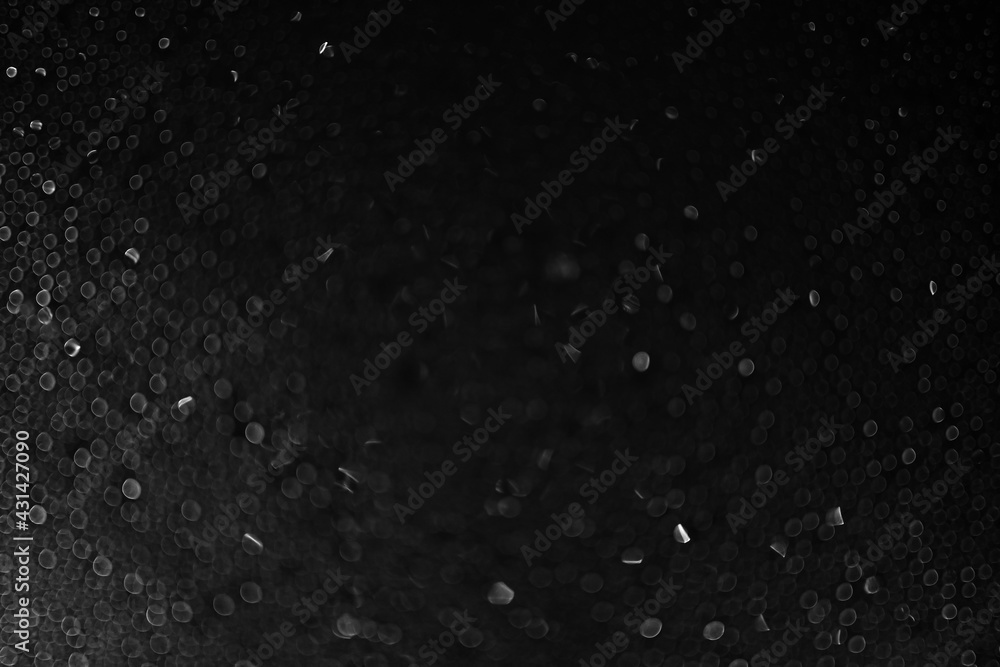 Drops of water and ice on the glass on a black background. Abstract texture dark bokeh background with copy space. Defocusing. High quality photo