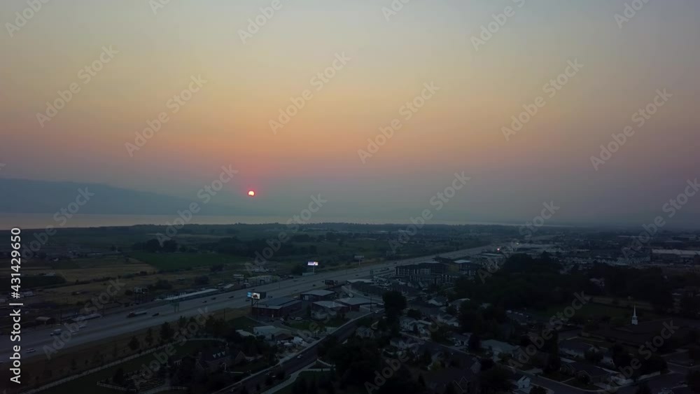 Beautiful aerial red sunset in a smoggy sky from summer wildfires. View of the sunset with mountains in the background and the freeway, park, and buildings in the foreground Beautiful aerial red sunset in a smoggy sky from summer wildfires. View of the sunset with mountains in the background and the freeway, park, and buildings in the foreground