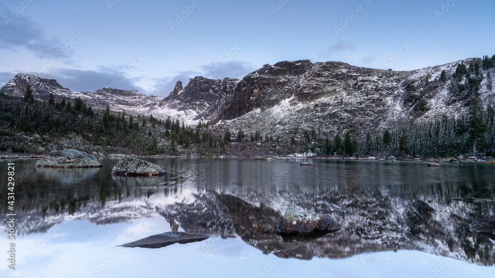 Lake in the natural park Ergaki among the mountains reflections of the mountains in the water in winter in the snow