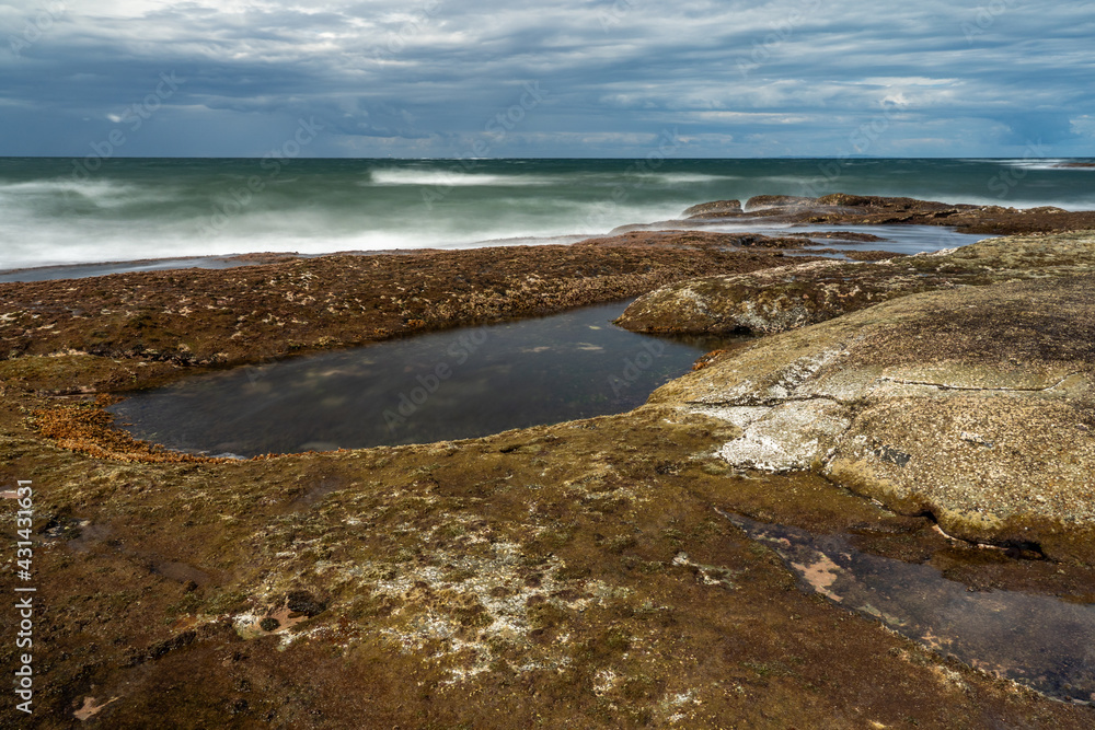 Green sea with a blue cloudy sky and rock pool Green sea with a blue cloudy sky and rock pool