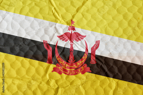 The national flag of Brunei on an uneven textured surface. photo