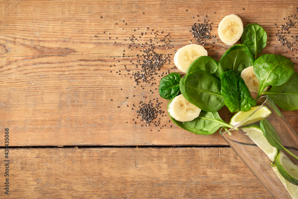 Healthy food concept. Ingredients for cooking detox smoothie. Glass with spinach, banana, lime and chia seeds on wooden table top view, copy space Healthy food concept. Ingredients for cooking detox smoothie. Glass with spinach, banana, lime and chia seeds on wooden table top view, copy space