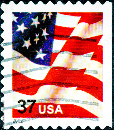 stamp printed in the United States, features waving US flag, first-class