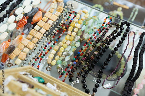 Collection of natural gemstone beads displayed for sale on shelf of jewelry boutique..