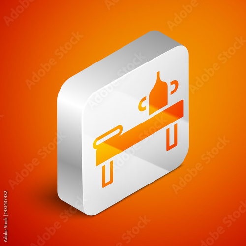 Isometric Massage table with oil icon isolated on orange background. Silver square button. Vector
