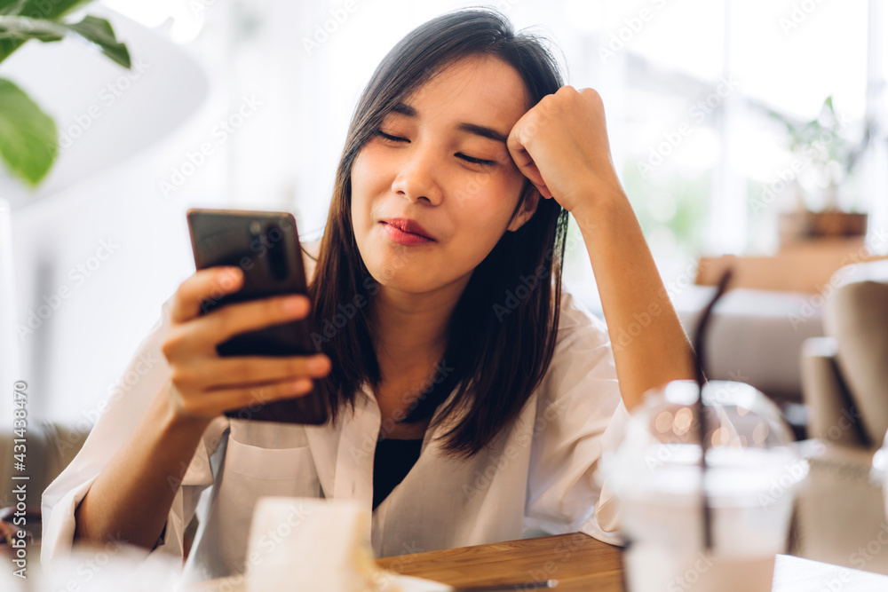 Obraz premium Portrait of smiling happy beautiful asian woman relaxing using digital technology smartphone.Young asian girl looking at screen typing message and playing game online or social media at cafe