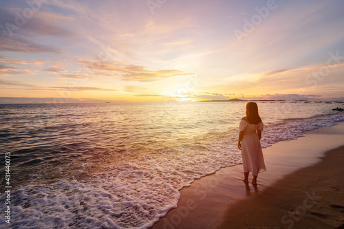 Lonely young woman walking and enjoying beautiful Sunset on the tranquil beach, Travel on summer vacation concept