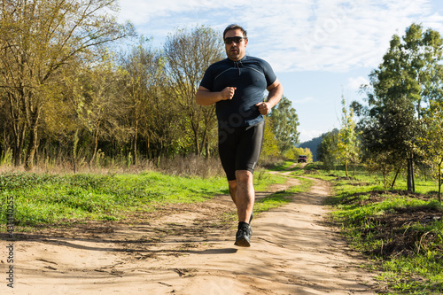 Overweight young man jogging in the park.