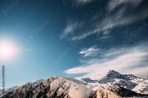 Stepantsminda  Georgia. Moonrise In Winter Night Starry Sky With Glowing Stars Over Peak Of Mount Kazbek Covered With Snow. Beautiful Night Georgian Winter Landscape