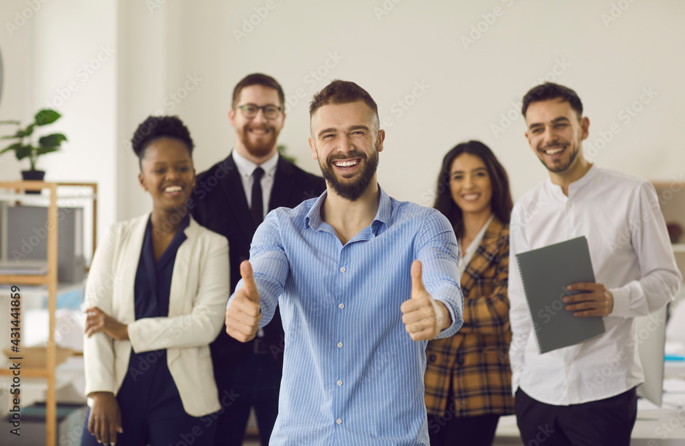 Happy smiling man team leader entrepreneur with thumbs up looking at camera standing together with group of multiracial millennial businesspeople on background. Teamwork, collaboration approval - obrazy, fototapety, plakaty 