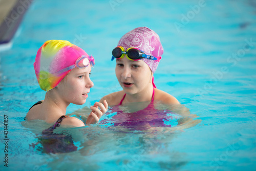 Two girls in swimming caps in the pool. Swimming section.