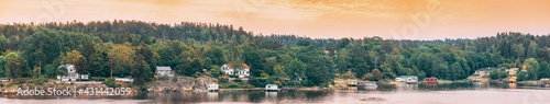 Sweden. Many Beautiful Swedish Wooden Log Cabins Houses On Rocky Island Coast In Summer Evening. Lake Or River Landscape. Panorama, Panoramic View.