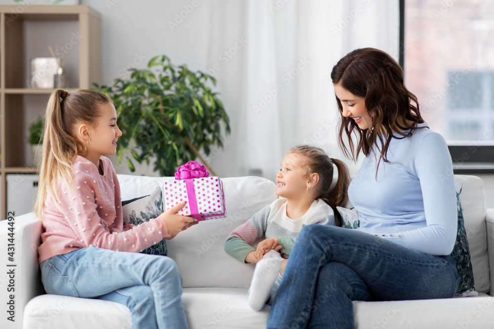people, family and holidays concept - happy girl giving birthday present to younger sister at home people, family and holidays concept - happy girl giving birthday present to younger sister at home