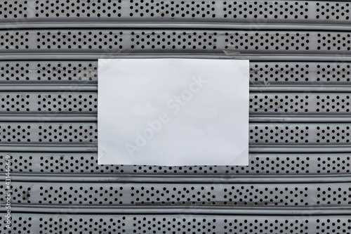 Empty white A4 paper sticked by clear adhesive tape on old gray metal rolling door background.
