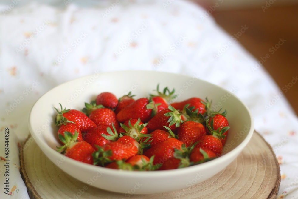 Bowl of fresh strawberries and wooden tray on a bed. Selective focus. Bowl of fresh strawberries and wooden tray on a bed. Selective focus.