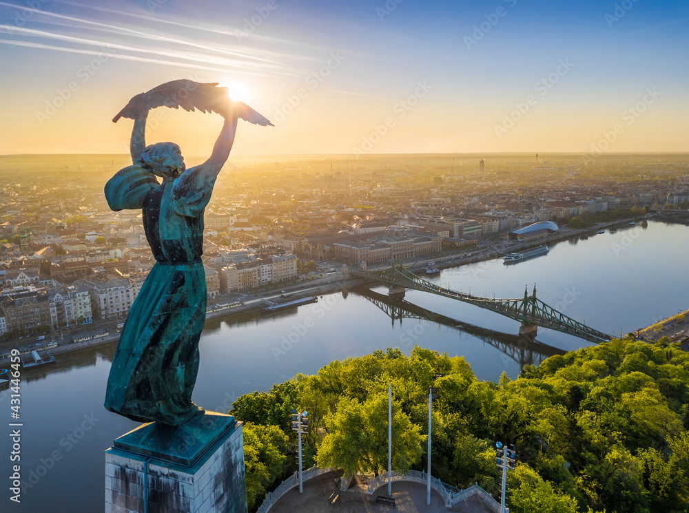 Budapest, Hungary - Aerial view from the top of Gellert Hill with Statue of Liberty, Liberty Bridge and skyline of Budapest at sunrise with clear blue sky