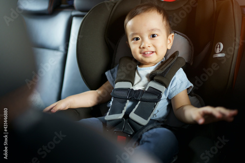 Asian little baby happy and fun while fastened belt and seat in the safety car seat. A boy looking his mother and smile in a car. photo