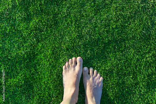 Bare female feet on green grass. Top view, copy space. Summertime, relax, healthy habit concept.