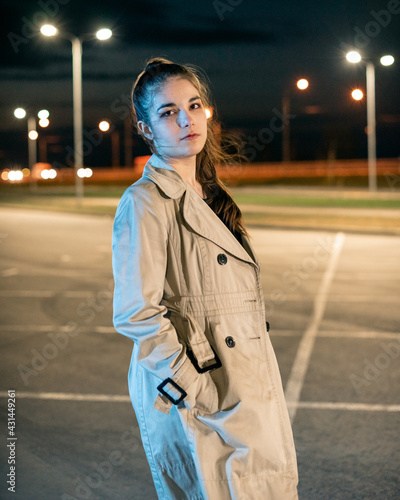 Young girl in a parking lot against the backdrop of the night city photo