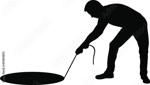 silhouette of man pulling rope from hole