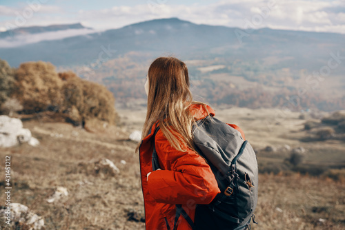 woman hiker in a jacket and with a backpack are resting in the mountains landscape Relax model