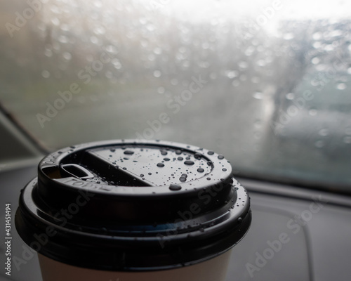 Drops on a paper cup of coffee in the car during the rain