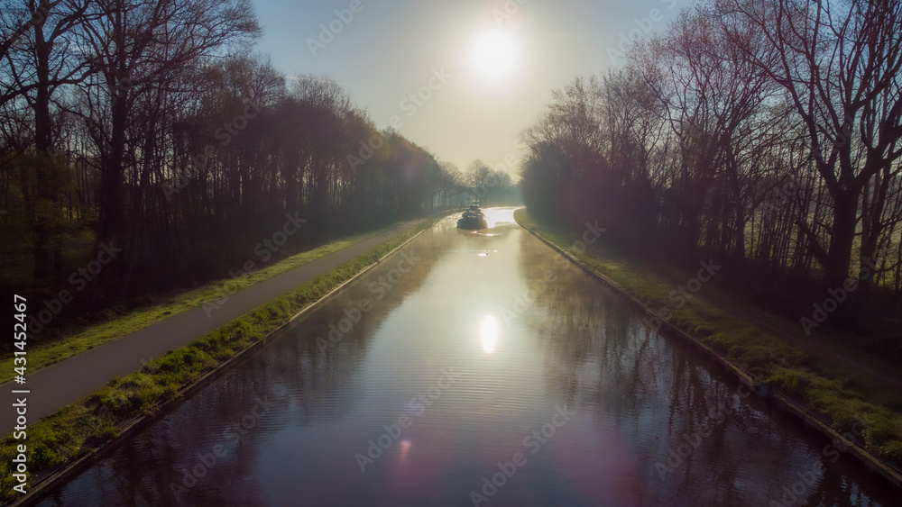 Aerial view of an Idillic river stream canal with grass banks and wild flowers and trees in a scenic landscape on a misty sunny spring morning sunrise day, taken with a drone. High quality photo Aerial view of an Idillic river stream canal with grass banks and wild flowers and trees in a scenic landscape on a misty sunny spring morning sunrise day, taken with a drone. High quality photo