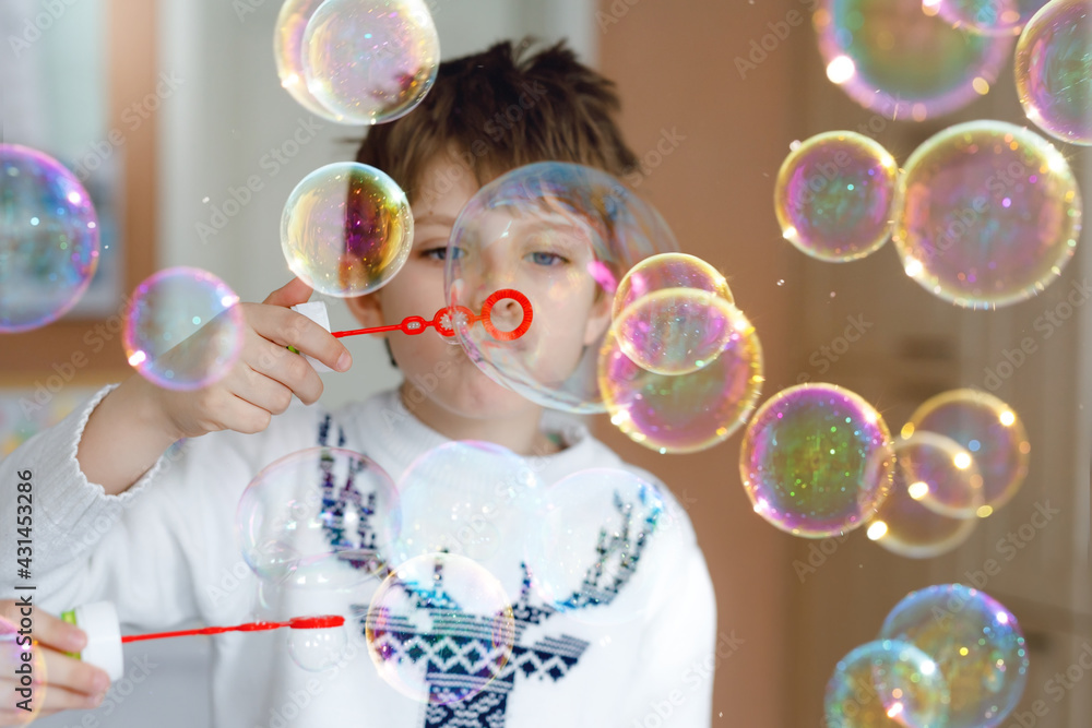 Happy little school boy playing with soap bubbles at home. Kid having fun. Child playing at school, making experiment Happy little school boy playing with soap bubbles at home. Kid having fun. Child playing at school, making experiment