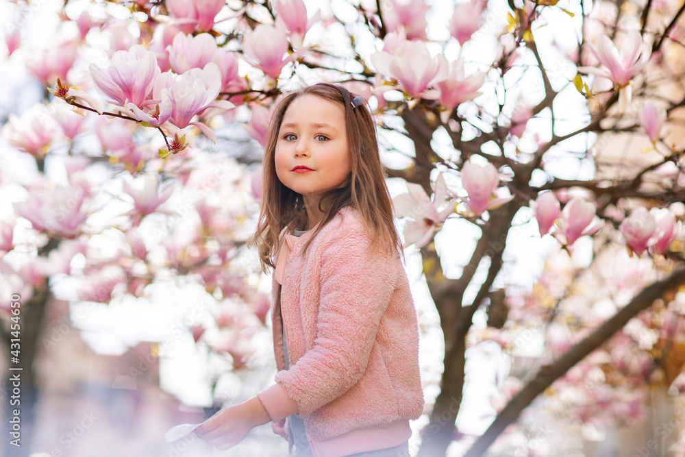Cute girl under blossom magnolia tree in spring Cute girl under blossom magnolia tree in spring
