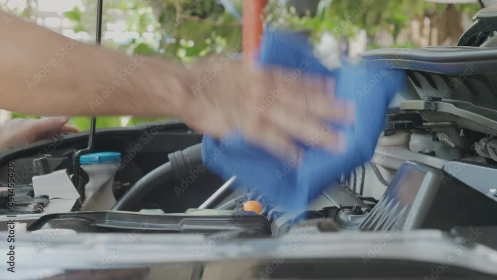 Closeup of man cleaning engine car room of his car with soft blue cloth at home, maintenance, wipes dust in the car Closeup of man cleaning engine car room of his car with soft blue cloth at home, maintenance, wipes dust in the car