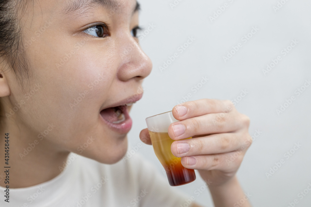Asian lady girl rinsing the mouth or gargling with medicine of medical disinfectant,protect against the Coronavirus COVID-19 in throat,disinfection of the oral cavity or bad breath,pharyngitis concept Asian lady girl rinsing the mouth or gargling with medicine of medical disinfectant,protect against the Coronavirus COVID-19 in throat,disinfection of the oral cavity or bad breath,pharyngitis concept