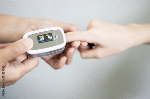 Fingertip pulse oximeter on the finger of young woman measuring heart rate (pulse) checking oxygen saturation (SpO2) level in the blood,diagnosis of Coronavirus or COVID-19 at home,health care concept