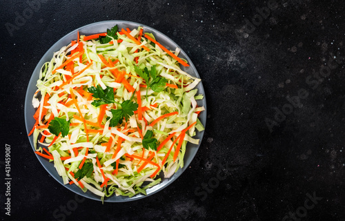 Coleslow cabbage salad with carrot on grey kitchen table. Top view, copy space