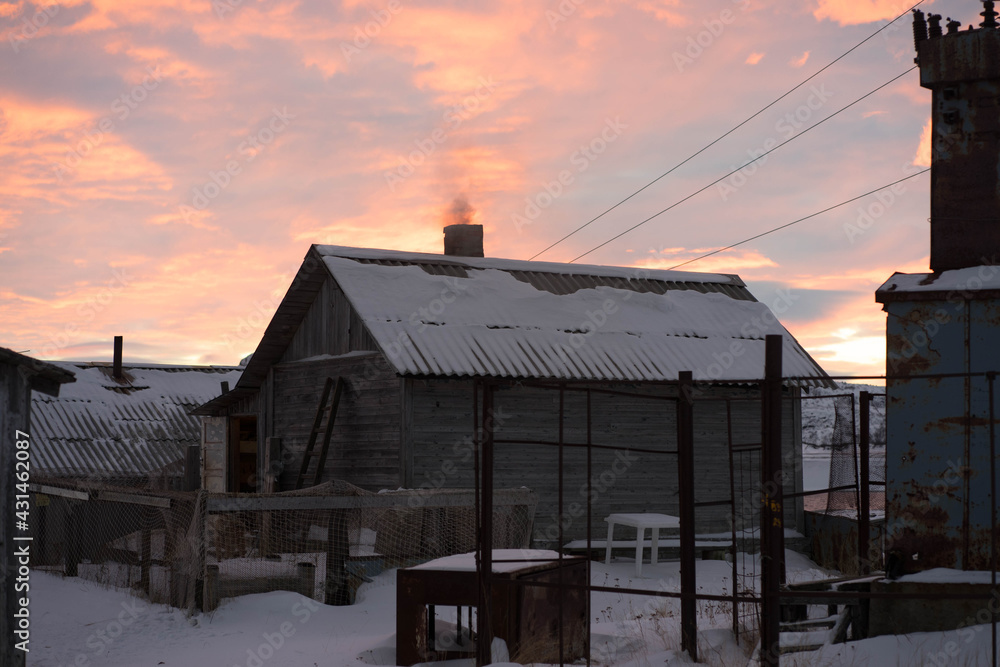 old wooden house in winter at sunset