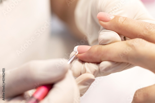 French manicure is the process of performing a procedure in a beauty salon by a manicure master. White gel polish and a fine brush. Close-up