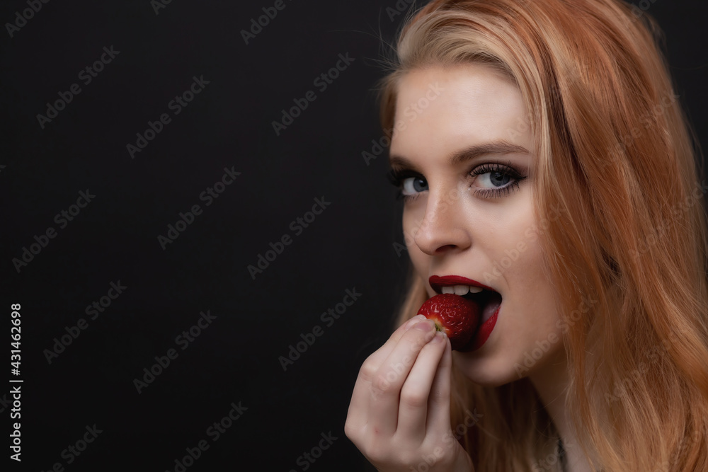 Portrait of attractive long hair young woman tasting fresh strawberry looking at the camera. Horizontally. Portrait of attractive long hair young woman tasting fresh strawberry looking at the camera. Horizontally.