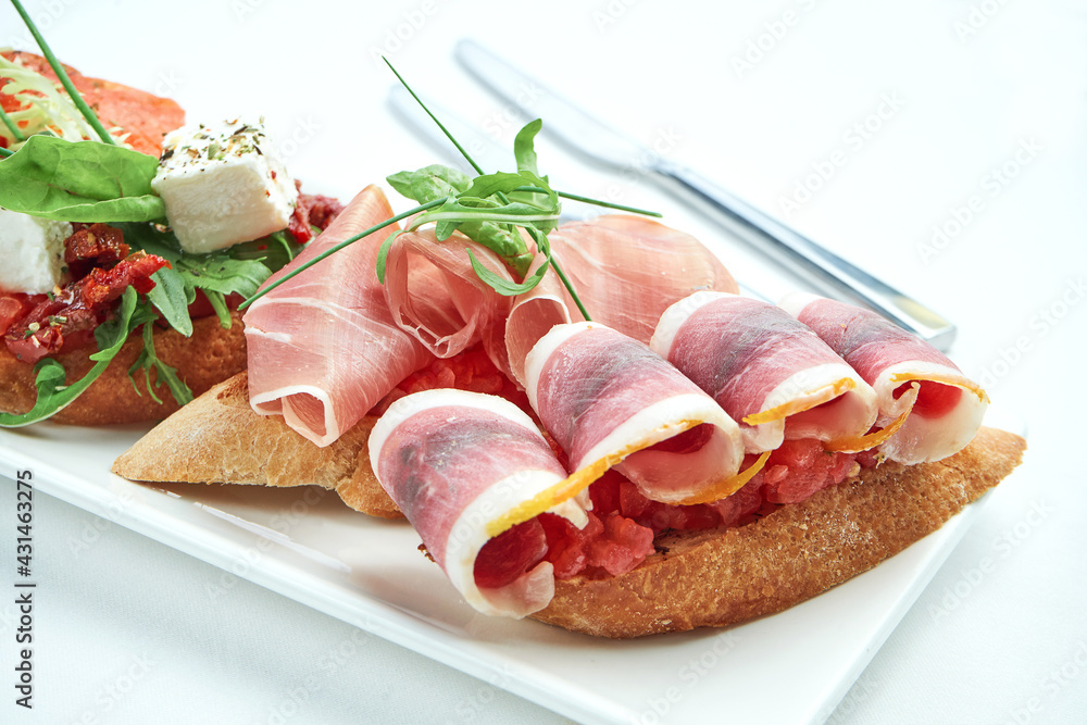 Set of delicious Italian bruschettas with ham, ham, tomatoes, salmon and cheese served with a glass of wine